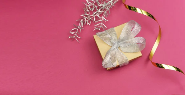 Gift box with silver and serpentine golden bow for a birthday party  Valentine\'s Day and New Year on a pink background