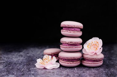 Macaron kurabiye tatlı pembe Lila Pembe çiçekler bir koyu siyah zemin üzerine Fransız