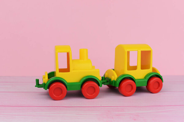 children's toy train for playing with cars yellow on a pink background