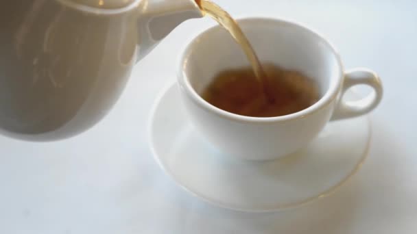 thé noir parfumé chaud est versé de la théière dans la tasse blanche 