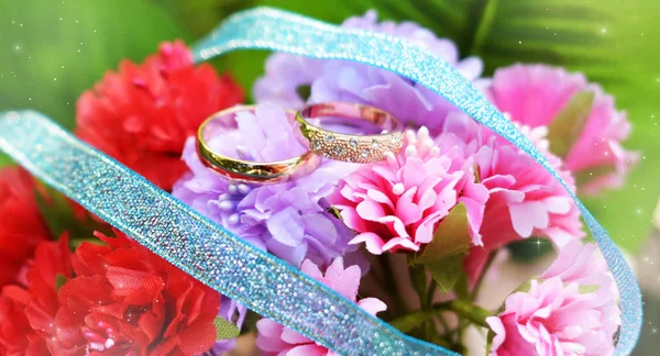 Wedding rings gold on the colors of red and pink for lovers — Stock Photo, Image