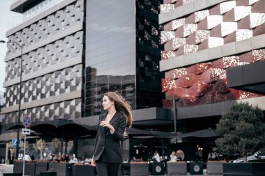Şehrin arka planında güzel siyah takım elbiseli genç ve çekici bir iş kızı..