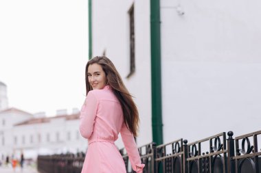 Pembe elbiseli genç, güzel bir kız şehirde dolaşıyor. Fotoğraf kapanışı ve genel plan. Bankta oturan kız.