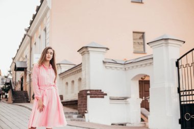 Pembe elbiseli genç, güzel bir kız şehrin güzel sokaklarında yürüyor. Şehirdeki bir kızın çok güzel portreleri..