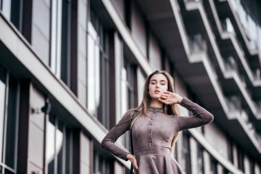 Genç bir kız omzunda bir çantayla ofisin yakınında yürüyor.