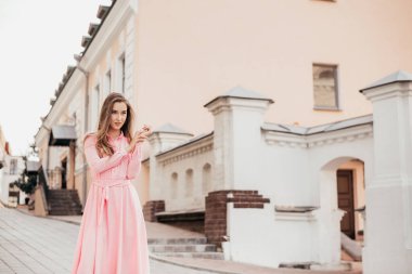 Pembe elbiseli genç, güzel bir kız şehrin güzel sokaklarında yürüyor. Şehirdeki bir kızın çok güzel portreleri..