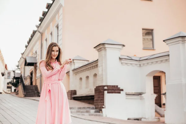 Ein junges, schönes Mädchen in einem rosafarbenen Kleid geht durch die schönen Straßen der Stadt. sehr schöne Porträts eines Mädchens in der Stadt. — Stockfoto