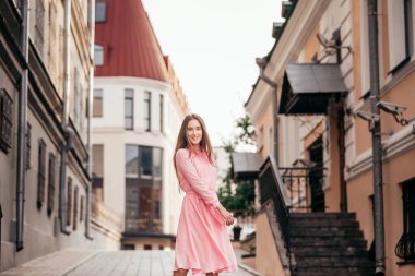 Pembe elbiseli genç, güzel bir kız şehrin güzel sokaklarında yürüyor. Şehirdeki bir kızın çok güzel portreleri..