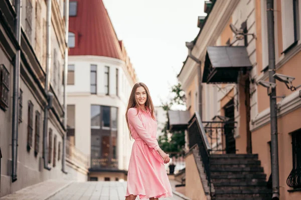 Ein junges, schönes Mädchen in einem rosafarbenen Kleid geht durch die schönen Straßen der Stadt. sehr schöne Porträts eines Mädchens in der Stadt. — Stockfoto