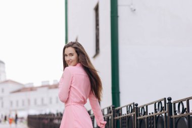 Pembe elbiseli genç, güzel bir kız şehirde dolaşıyor. Fotoğraf kapanışı ve genel plan. Bankta oturan kız.