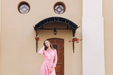 Pembe elbiseli genç, güzel bir kız şehirde dolaşıyor. Fotoğraf kapanışı ve genel plan. Bankta oturan kız.