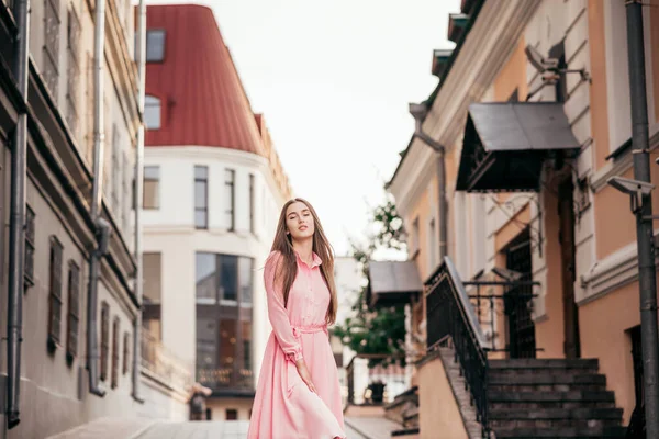一个穿着粉红衣服的年轻漂亮的姑娘穿过城里漂亮的街道。 城市里一个女孩的美丽画像. — 图库照片