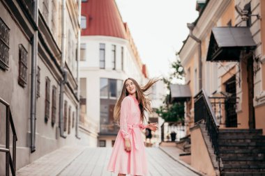 Pembe elbiseli genç, güzel bir kız şehrin güzel sokaklarında yürüyor. Şehirdeki bir kızın çok güzel portreleri..