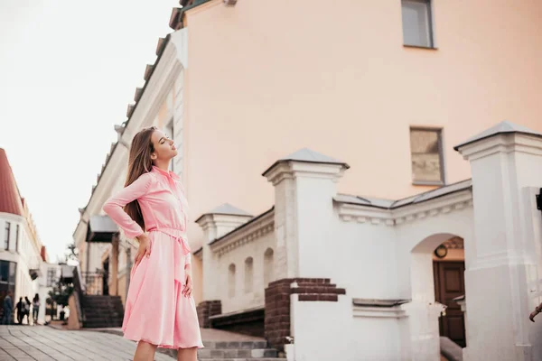 Uma jovem, linda menina em um vestido rosa caminha pelas belas ruas da cidade. Retratos muito bonitos de uma menina na cidade . — Fotografia de Stock