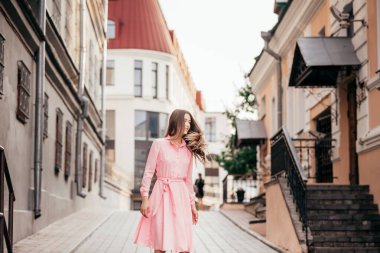Pembe elbiseli genç, güzel bir kız şehrin güzel sokaklarında yürüyor. Şehirdeki bir kızın çok güzel portreleri..
