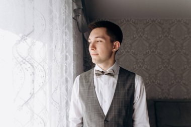 Damat pencerenin yanında duruyor. Düğün günü..