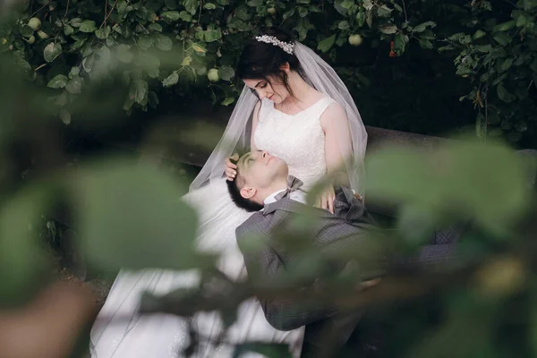 Recém-casados sentados num banco. Eles olham um para o outro apaixonados . — Fotografia de Stock