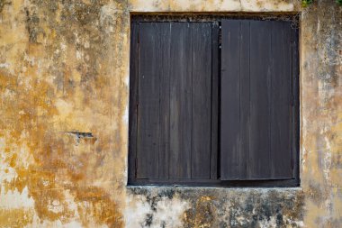 Sarı sıva duvar ve kopya alanı üzerinde ahşap kepenkleri ile eski pencere