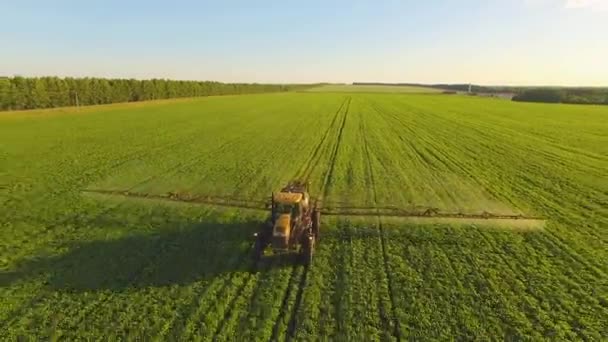 Трактор распыляет пестициды на соевое поле с распылителем весной. Воздушная стрельба из коптера — стоковое видео