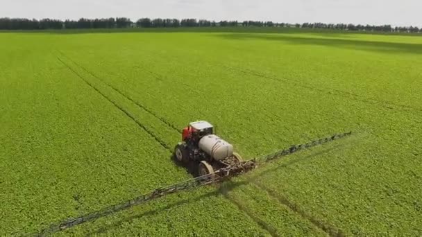 Trattore che spruzza pesticidi sul campo di soia con spruzzatore in primavera. Sparatoria aerea quadricottero — Video Stock