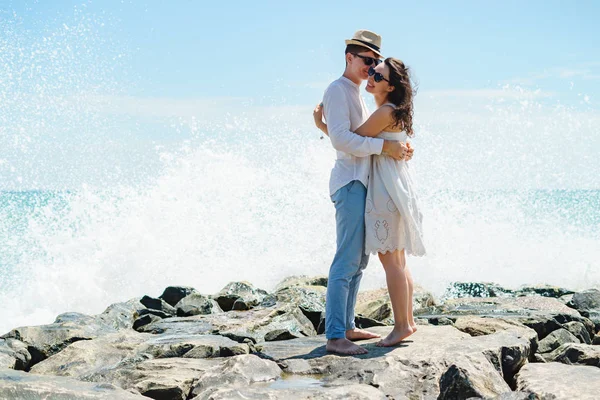 Молодая пара любовников, парень и девушка в океане, в белой одежде на камнях. — стоковое фото