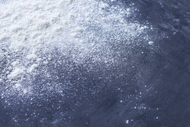 Beyaz kabartma buğday unu koyu mavi dokulu grunge arka plan üzerinde resmin köşesine serpilir. Sığ alan derinliği