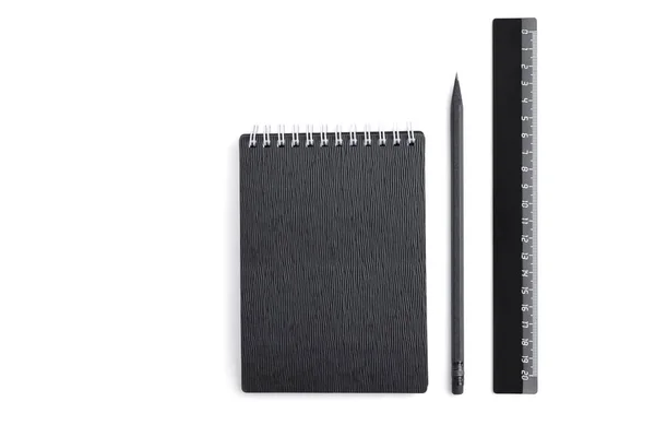 Platt låg anteckningsbok med svart texturerat omslag, svart penna och svart glänsande linjal isolerad på en vit bakgrund. Affärs-eller utbildningskoncept. Tomt utrymme för text — Stockfoto
