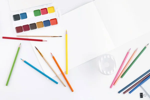 明亮的水彩颜料的平面布局组合，用于绘图的画笔，分散的彩色铅笔和用于绘制文本或图片的空白页的相册. — 图库照片