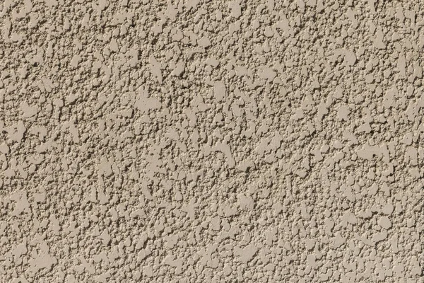 Le mur extérieur du bâtiment recouvert de stuc décoratif texturé beige éclairé par les rayons lumineux du soleil. Vieux fond texturé rugueux — Photo