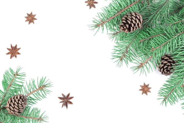 Top view of a festive composition of green fluffy Christmas tree branches with brown forest natural cones and star anise with empty space in the center isolated on white background — Stock Photo, Image
