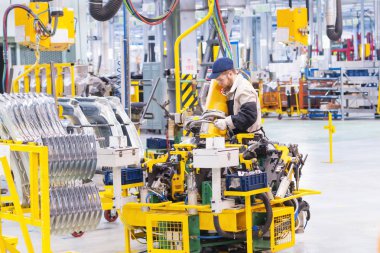 İzhevsk, Rusya - 15 Aralık 2018: İş yerindeki bir erkek kaynakçı, hareket edebilen bir kaynak makinesinin küçük parçalarını bir otomobil fabrikasında manipülatör şeklinde kaynak yapar.