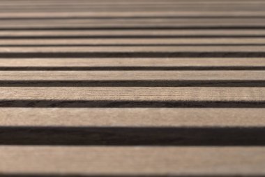 Güneşli bir günde, bir park bankında, sığ bir tarlada, kahverengi ahşap tahtalar üzerinde yan görüş. Soyut moda modern doku arkaplanı