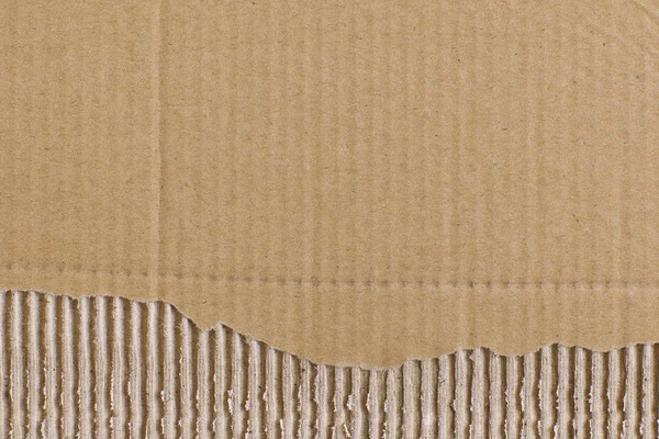 Vista superior primer plano corrugado rayas hoja marrón de cartón con un pedazo de papel arrancado de abajo. Fondo abstracto de textura moderna de moda —  Fotos de Stock