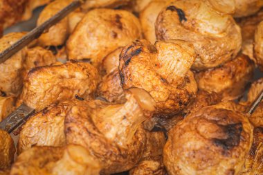 Kömür ızgarasında pişirilmiş şişler üzerinde şampiyonlar. Bir sokak tezgahında mantar kızartması, sığ bir alan derinliğinde. Izgarada kızartılmış baharatlı lezzetli mantarlar. Seçici odak.