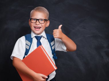 Kırmızı kitapla gülümseyen başarılı genç öğrenci fotokopi aletiyle başparmağını koyu arkaplanda gösteriyor.