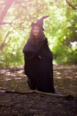Halloween. bir gülümseme ile genç çekici cadı. küçük cadı. yüksek değil. bir şapka ve yağmurluk içinde cüce