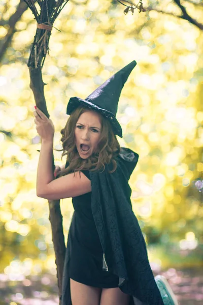 万圣节 这场战斗是一个带着扫把和帽子的女巫 情感女巫迷人的女孩 — 图库照片