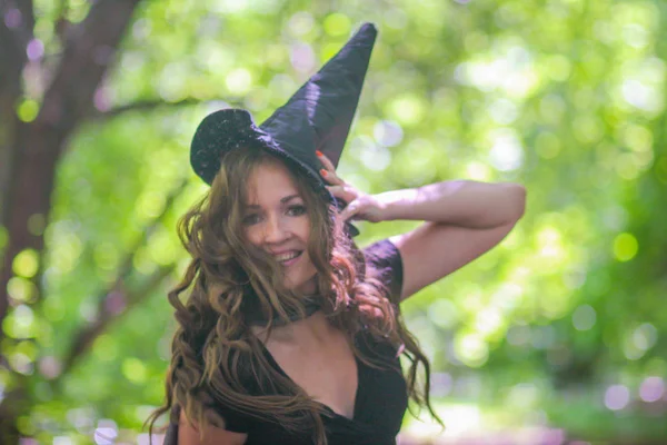 在森林中的树木之间的灵灵甜蜜 微笑和快乐的仙女卷曲的头发和在帽子 — 图库照片