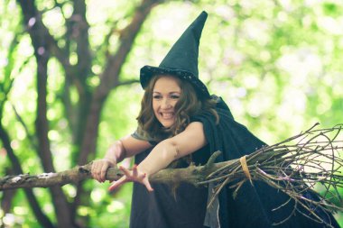 Witch on Halloween. Portrait of a cute girl. mischievous sorceress. attractive and sexy girl with a broom and a witch hood