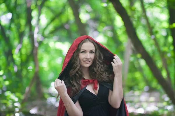 一个戴着红帽子的女巫在森林中间 有吸引力的女孩万圣节魔术 仙女微笑 — 图库照片