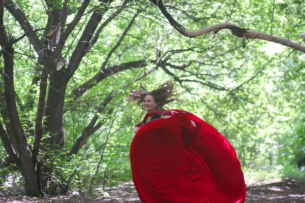 森のハロウィーンの中の赤いマントのリード 魅力的な女の子ハロウィーンの魔法をエスケープ — ストック写真