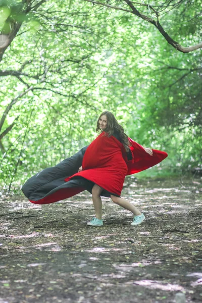 Super woman. sexy girl in a red cloak. among the forest. jumping that would fly up