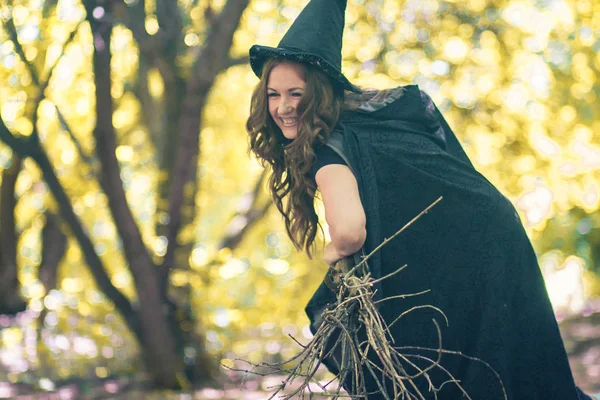 魔女のハロウィン森の中で手にほうきを持つ美しい魔女 — ストック写真