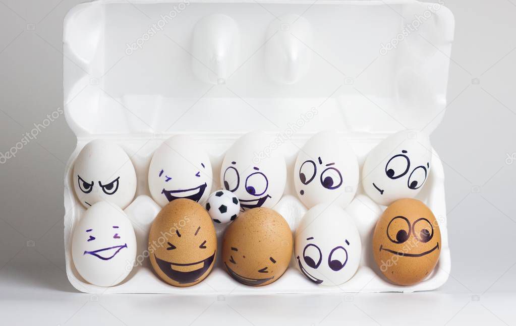 football is funny .. funny eggs with painted faces with a small soccer ball. white and brown eggs