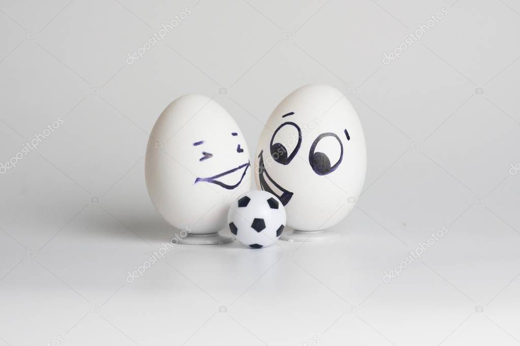 football is ridiculous. funny eggs two pieces. with painted faces with a small soccer ball. white eggs. sheet horizontal orientation