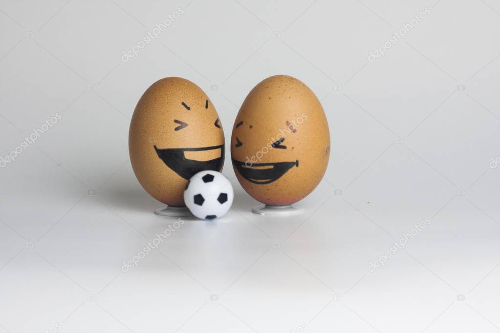 football is ridiculous. funny eggs two pieces. with painted faces with a small soccer ball. brown eggs. sheet horizontal orientation