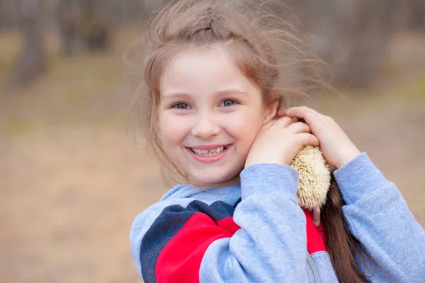 Conceito de sorriso. A menina ri e brinca com um ouriço . — Fotografia de Stock