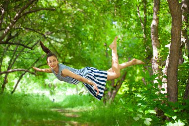 Uçuş konsepti. Güzel bir kız yeşil bir ormanda uçuyor..