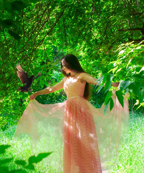 美しいです女の子でピンクドレスに鳥とともに彼女の腕. — ストック写真
