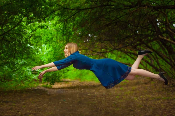 Het concept van levitatie. Een vrouw vliegt door het bos. — Stockfoto